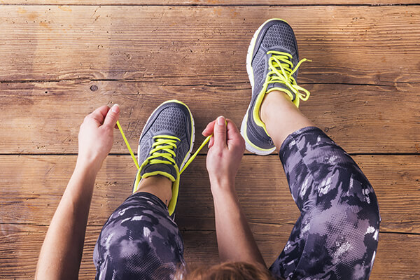 woman preparing for fitness in recovery day one by tying her shoes