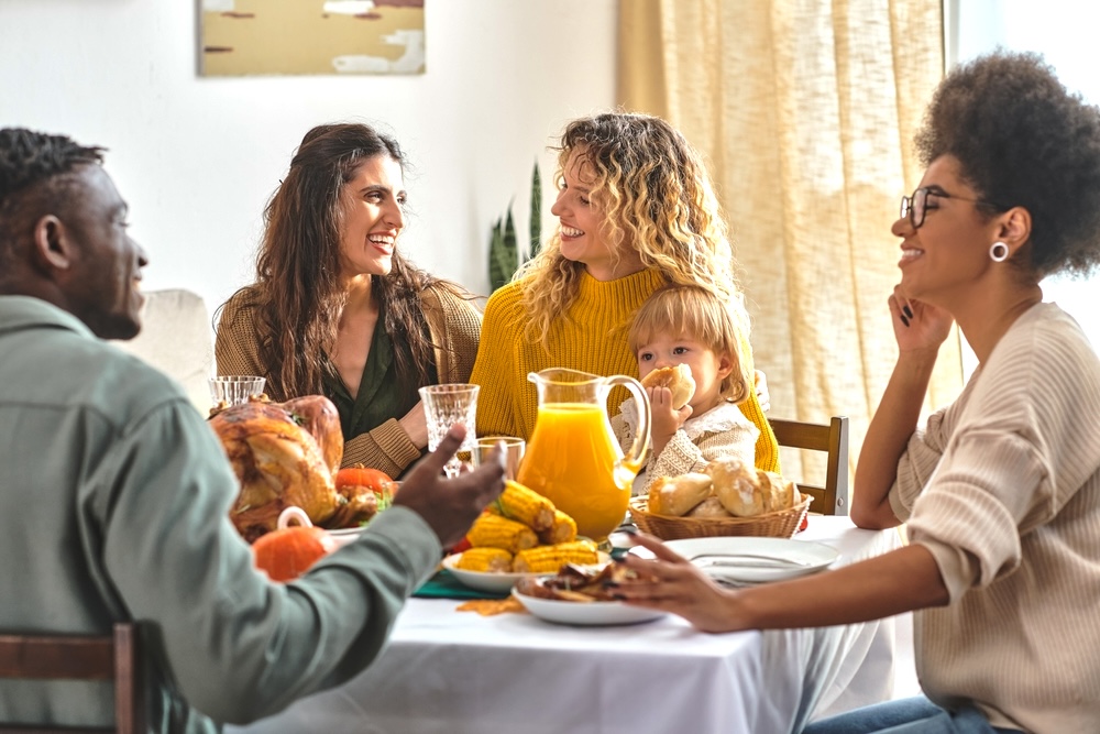 Happy family talking and laughing near lgbt family on Thanksgiving day