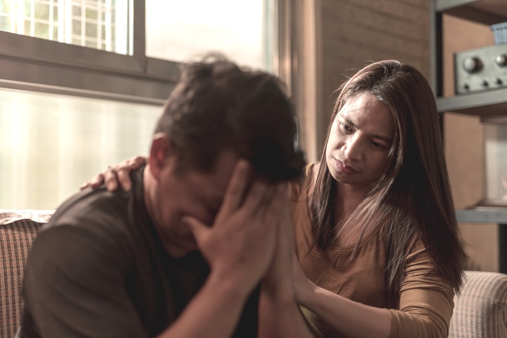 Woman comforts her addicted partner who is frustrated and depressed