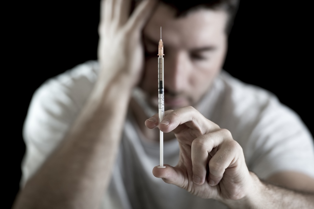 Man holding a syringe with heroin