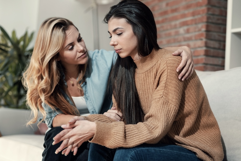 Female comforting her friend who is grieving due to the loss of a loved one